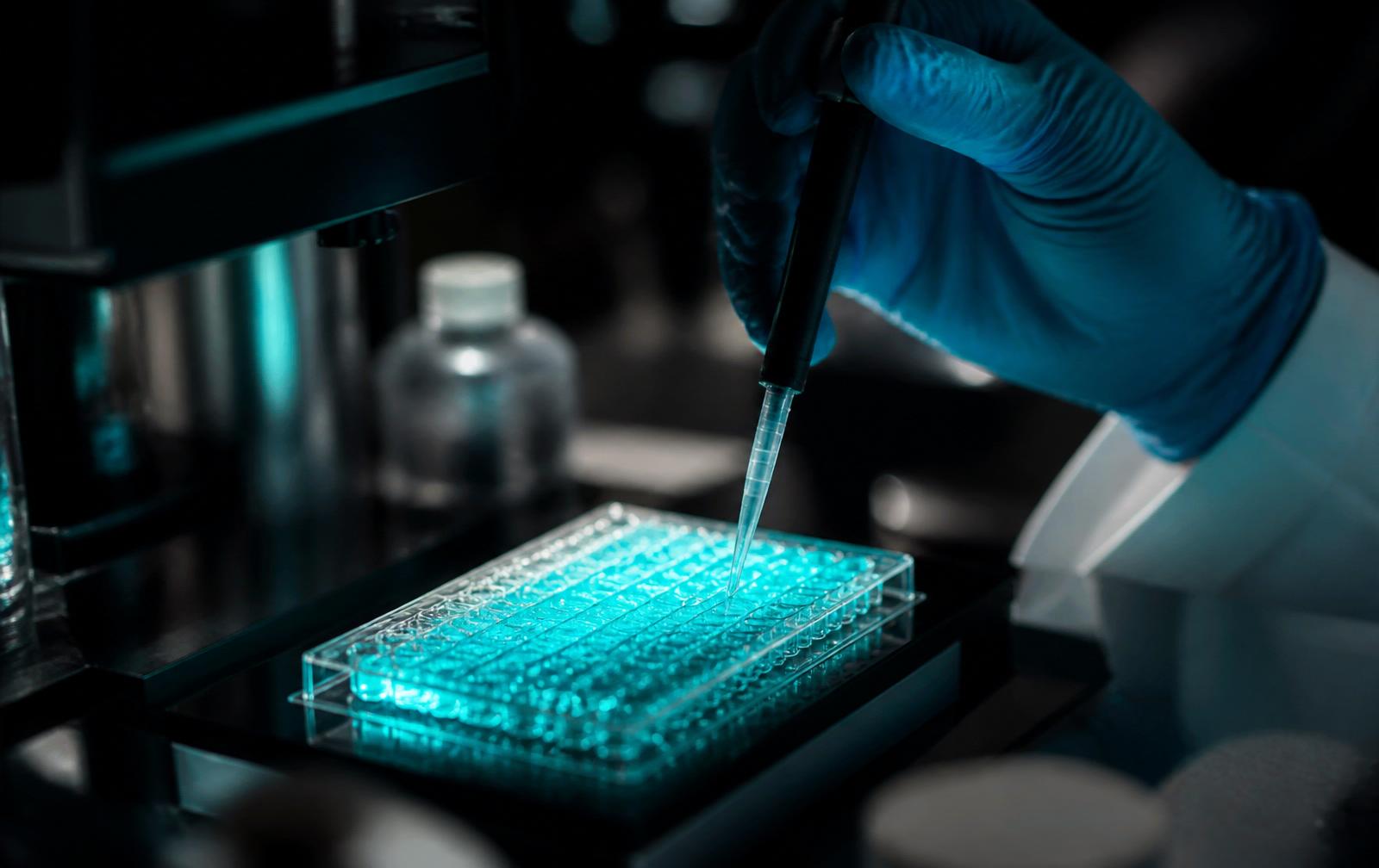Laboratório científico com pipeta e microplaca fluorescente